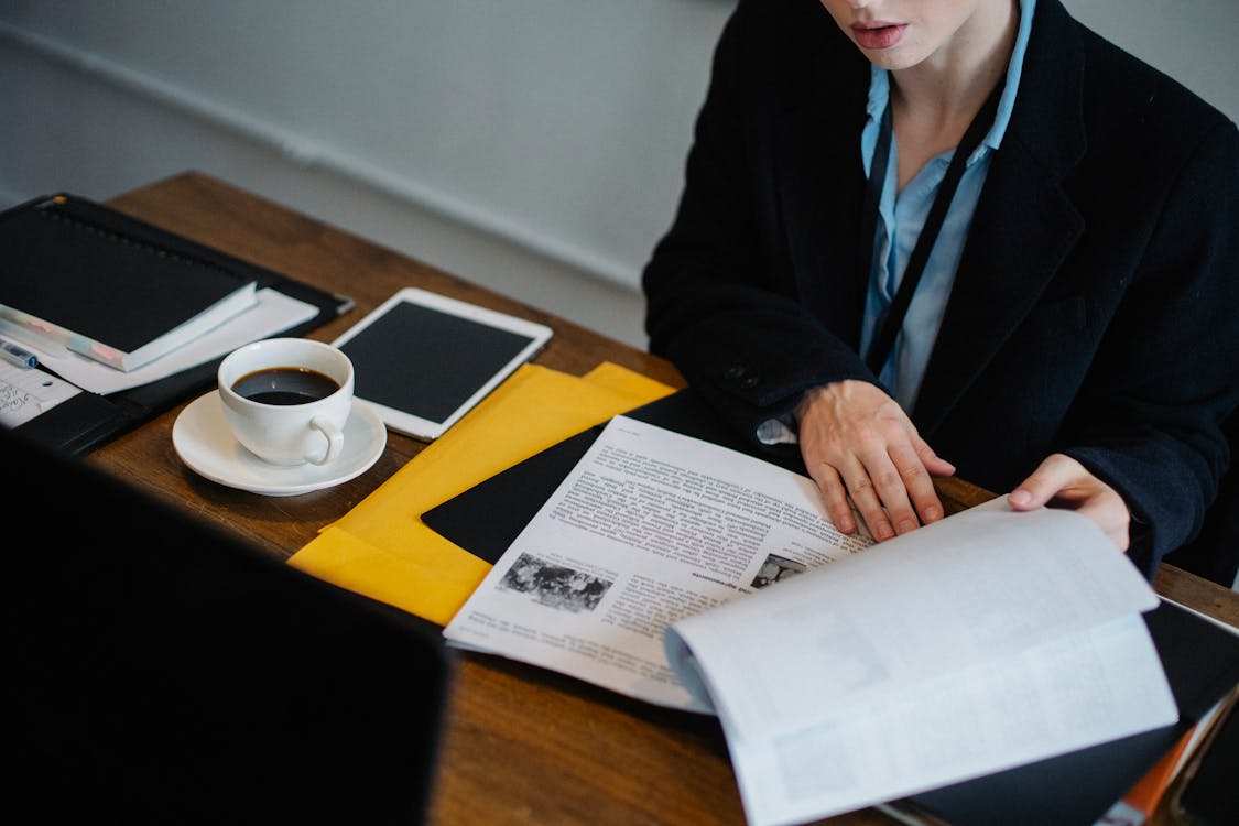 A professional reviewing a stack of appraisal documents and compliance reports on a desk.